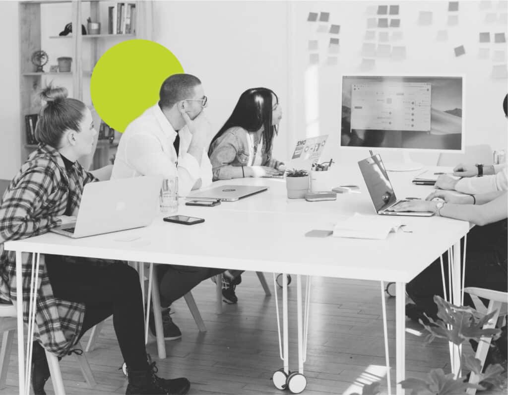In a conference room, a diverse group watches a customer retention marketing webinar on a screen