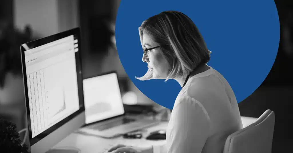 Woman sitting at a computer desk looking at marketing data.