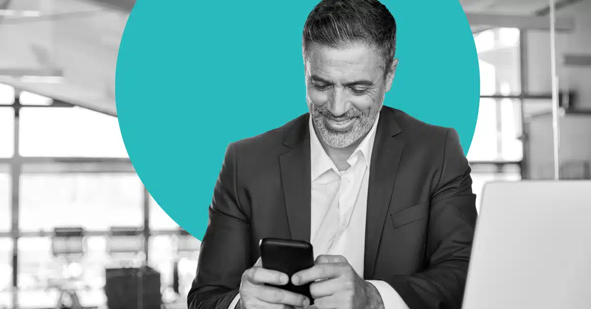 a businessman smiles at his mobile phone to illustrate customer retention marketing
