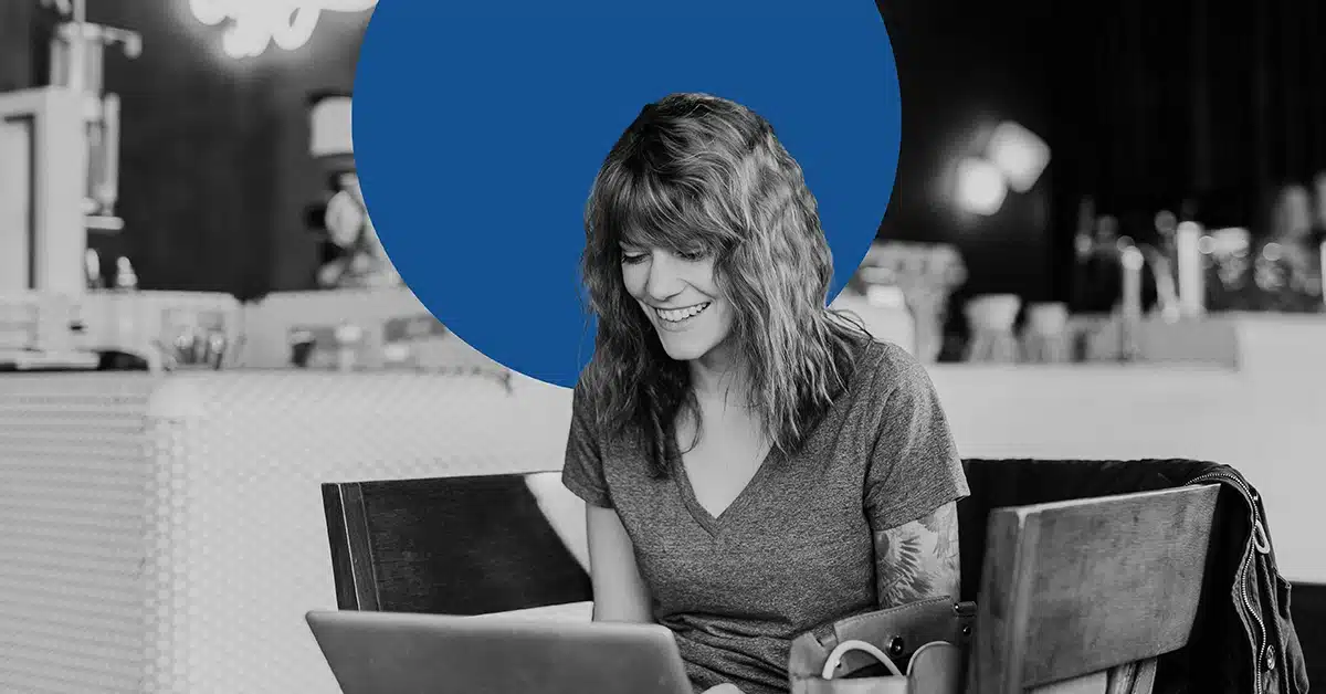 Woman smiling as she looks over her earned media on her laptop.