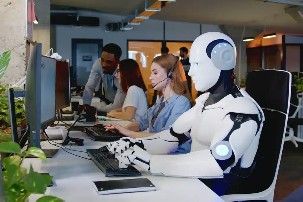 Robot working at computer among people to illustrate the idea of using AI to improve a marketing campaign.