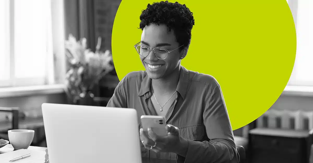 Smiling social media manager working on her computer and mobile device.