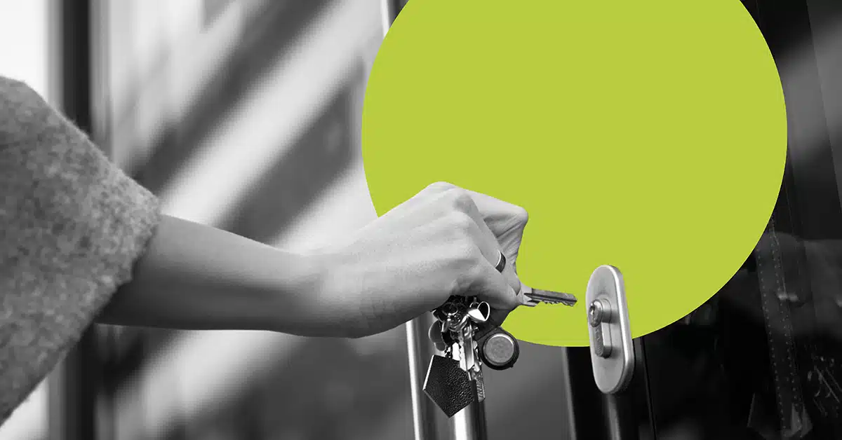 A hand uses keys to unlock a door.